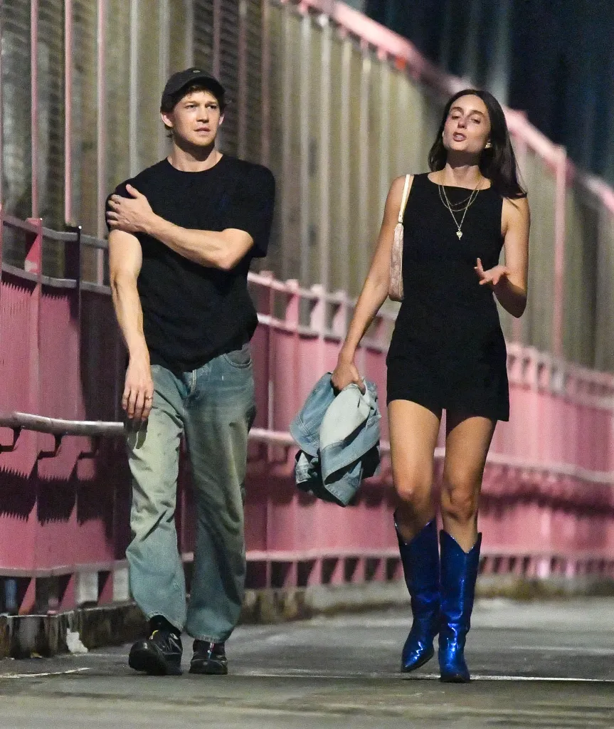 Joe Alwyn and Mary Beth Barone walking together on a New York City street at night.