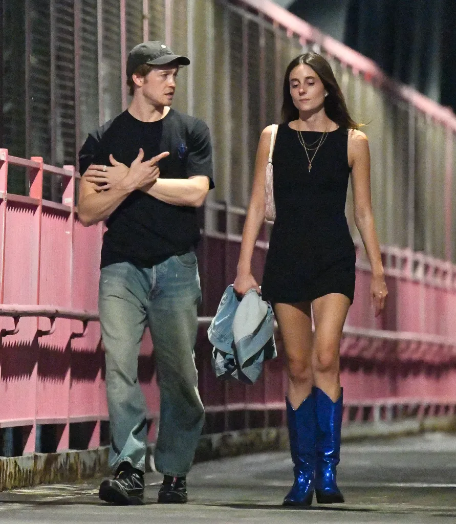 Joe Alwyn and Mary Beth Barone walking together on a New York City street at night.