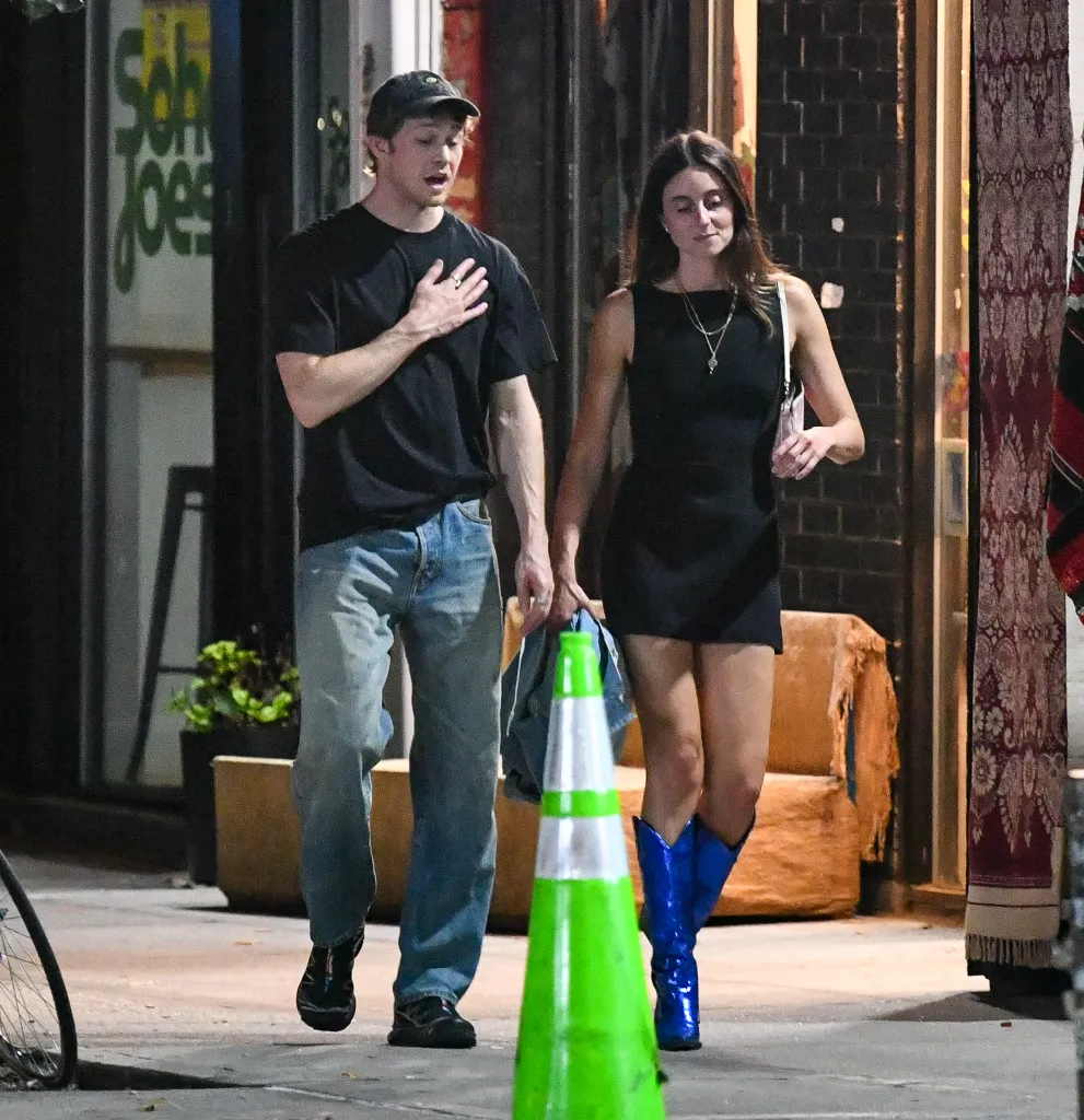 Joe Alwyn and Mary Beth Barone walking on a street at night.