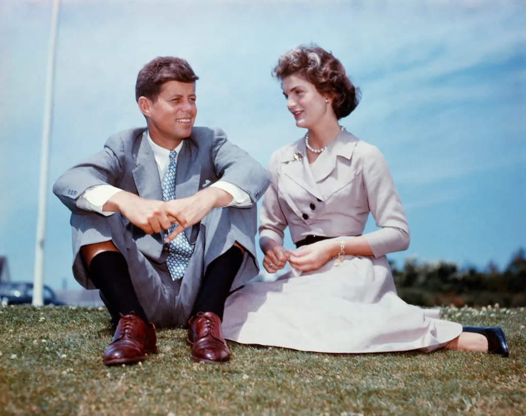 John F. Kennedy and Jacqueline Bouvier sit together on the grass at his family home in Hyannis Port, Massachusetts.