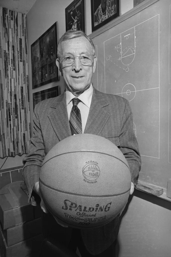 UCLA basketball coach John Wooden holding a basketball.