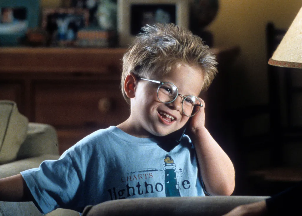 Jonathan Lipnicki smiling while talking on a phone in a scene from the film 'Jerry Maguire'.
