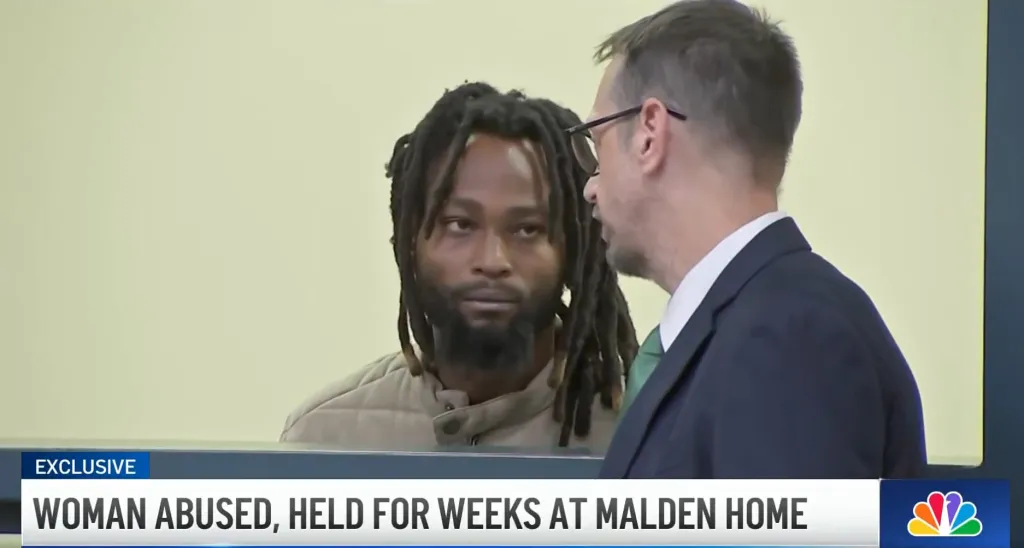 Jordende Pierre in a courtroom next to a man in a suit.