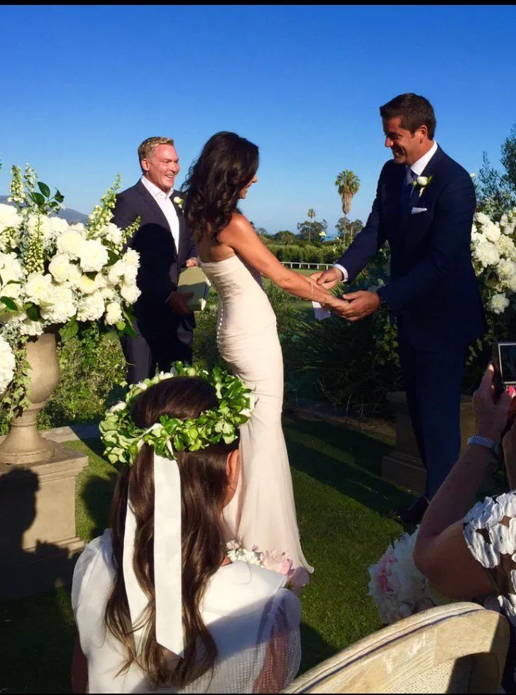 Liz Cho and Josh Elliott holding hands at their wedding.