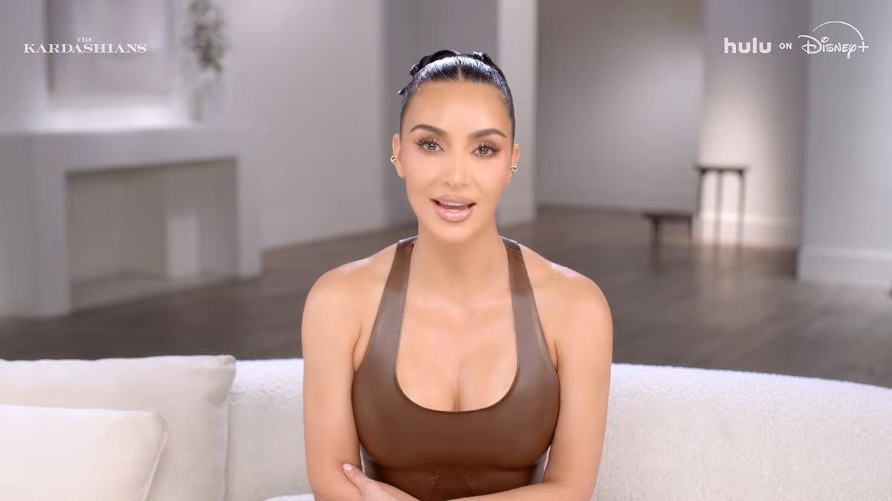 Kim Kardashian in a brown halter top on a white couch.