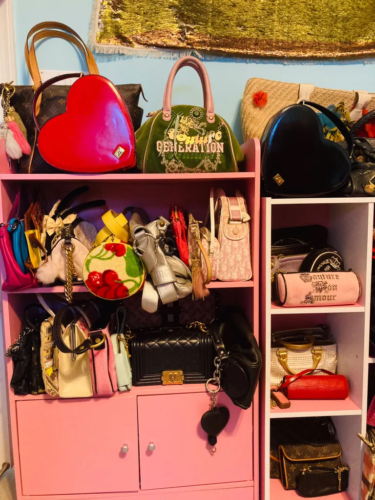 A pink shelving unit filled with various designer handbags, including Juicy Couture and Louis Vuitton.