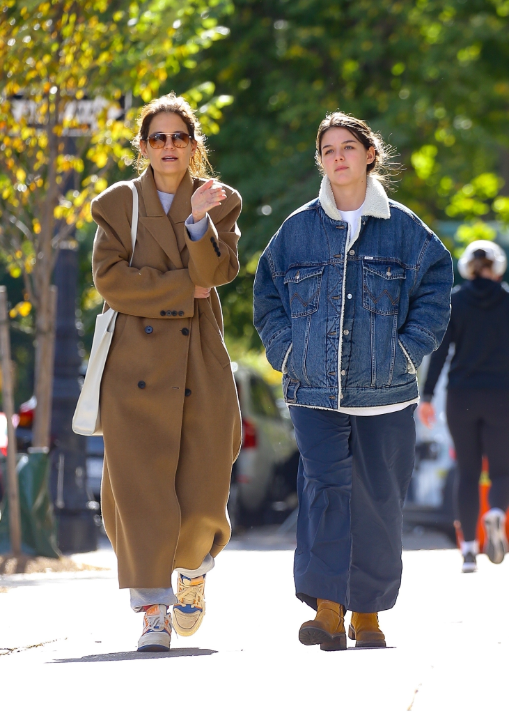 Katie Holmes, in a brown coat, and Suri Cruise, in a denim jacket and blue pants, walk together in New York City.