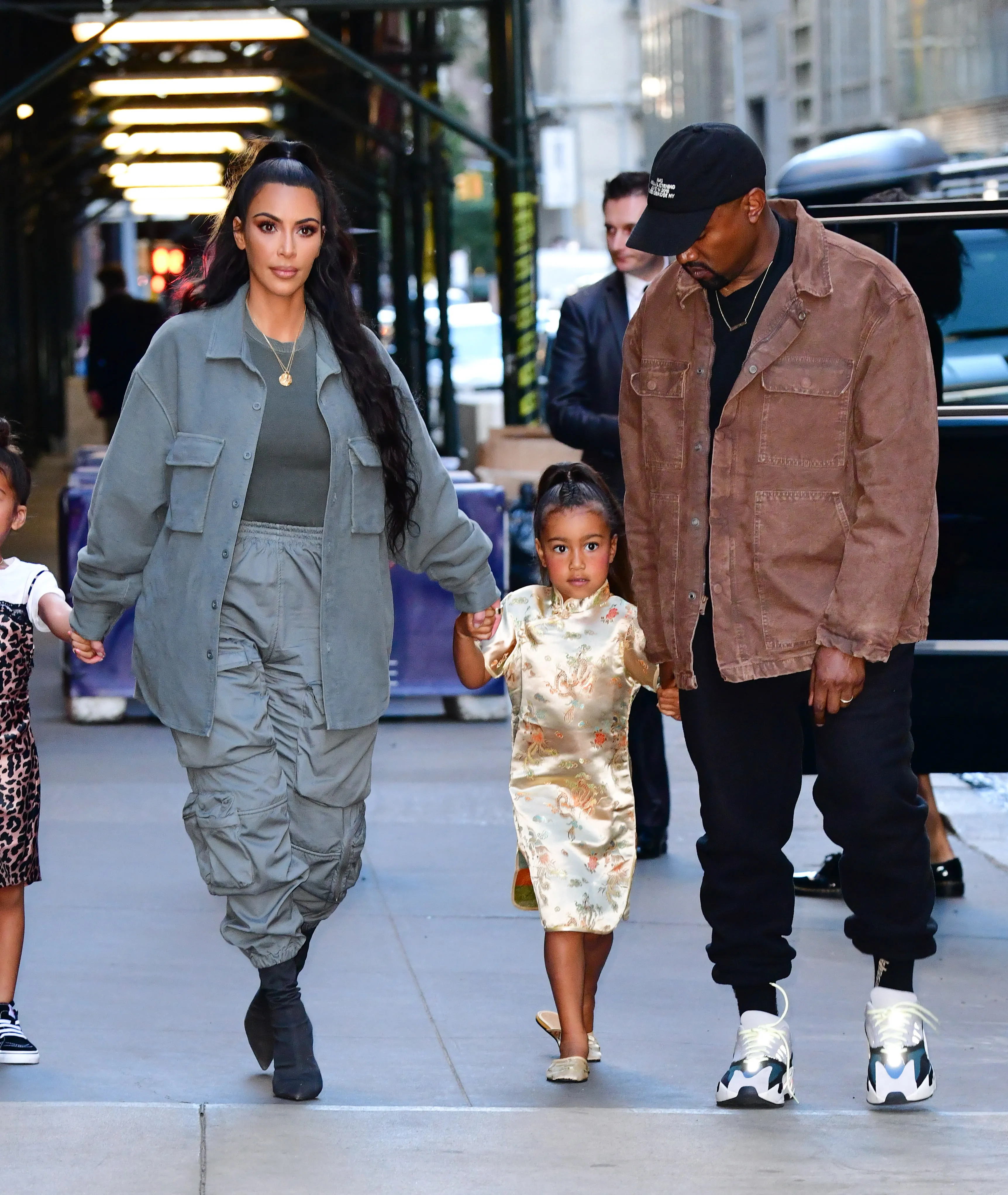 Kim Kardashian, North West, and Kanye West walk on a New York City sidewalk.