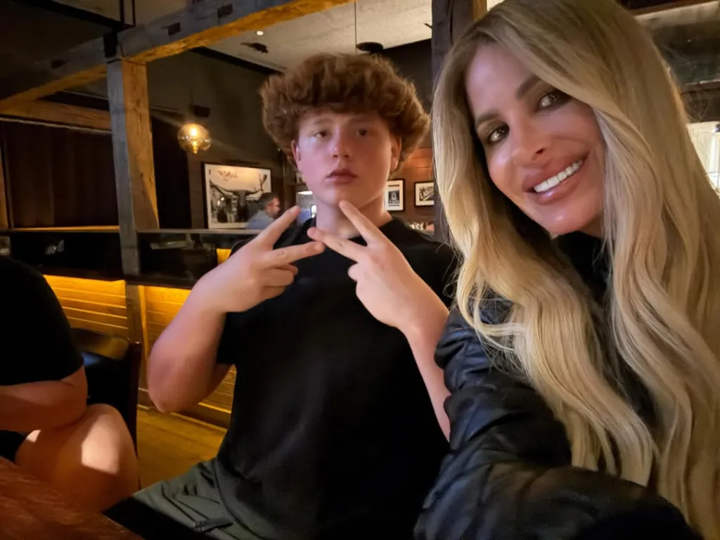 Kim Zolciak and her son KJ Biermann sitting at a table.