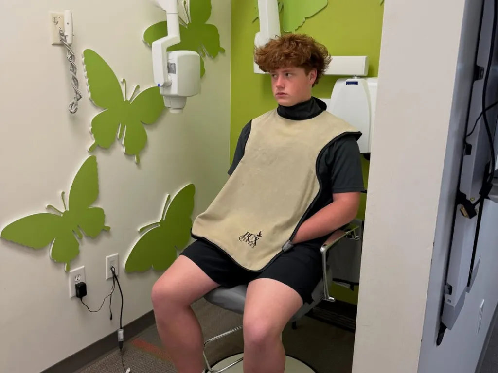 KJ Biermann in a dental office wearing a protective bib.