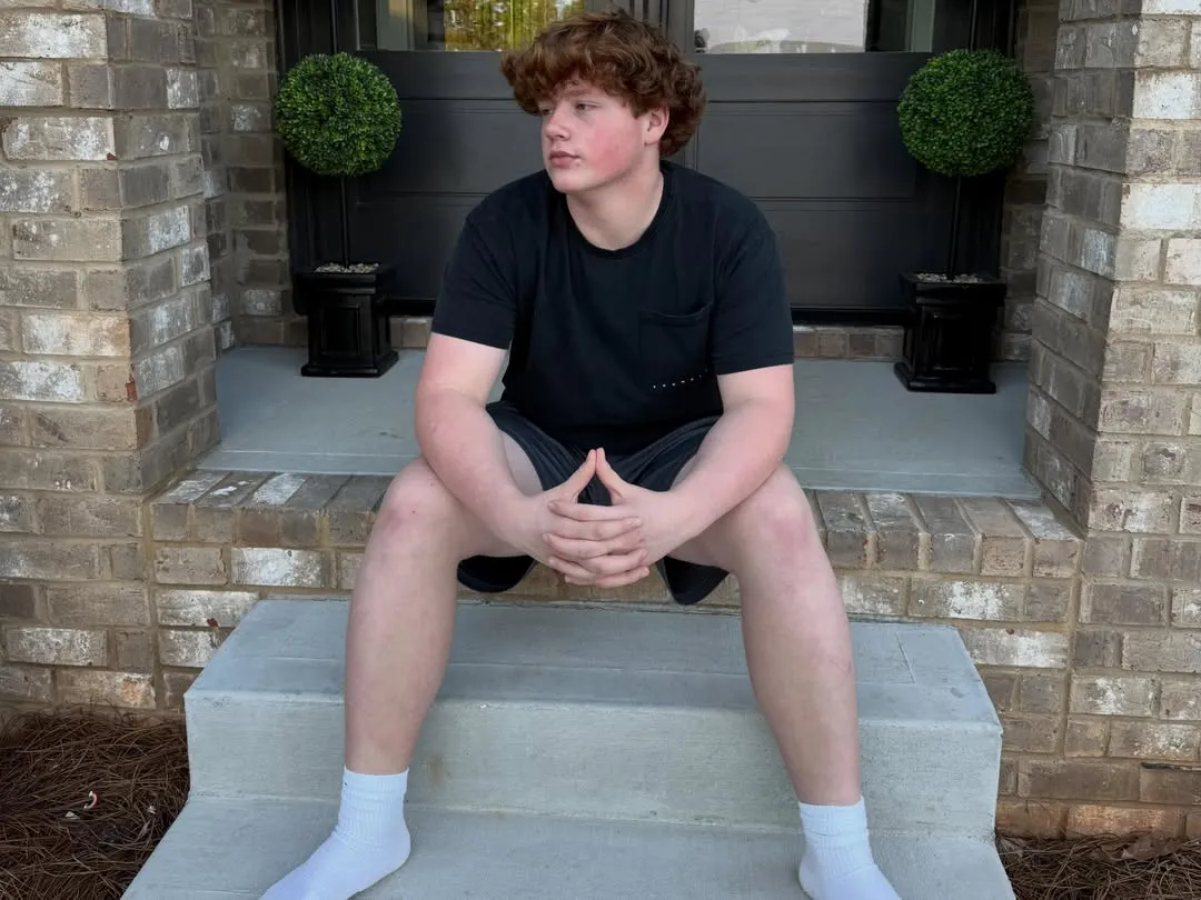 Kim Zolciak's son, KJ Biermann, sitting on steps.