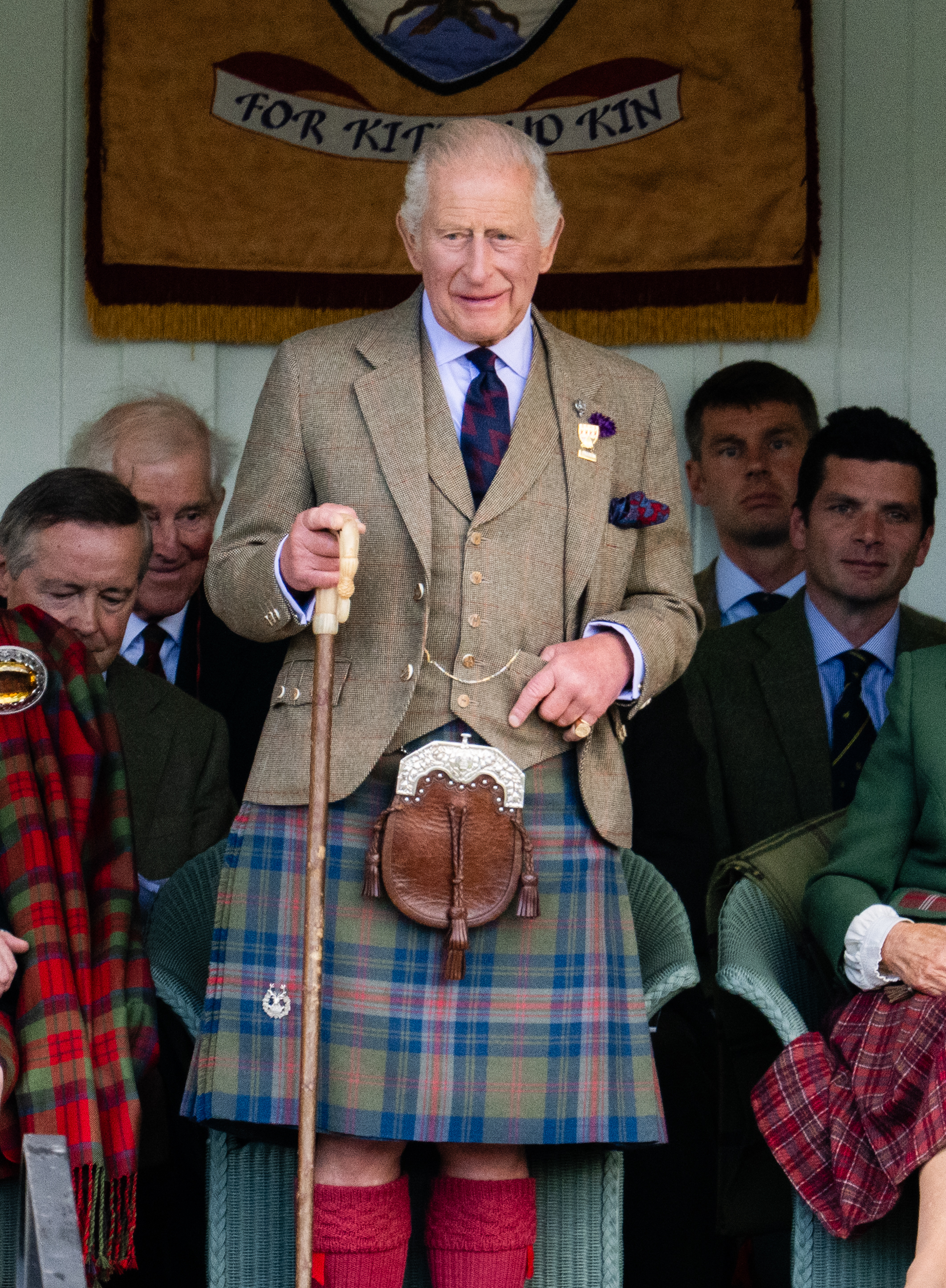 King Charles III in a kilt holding a walking stick at The Braemar Gathering.