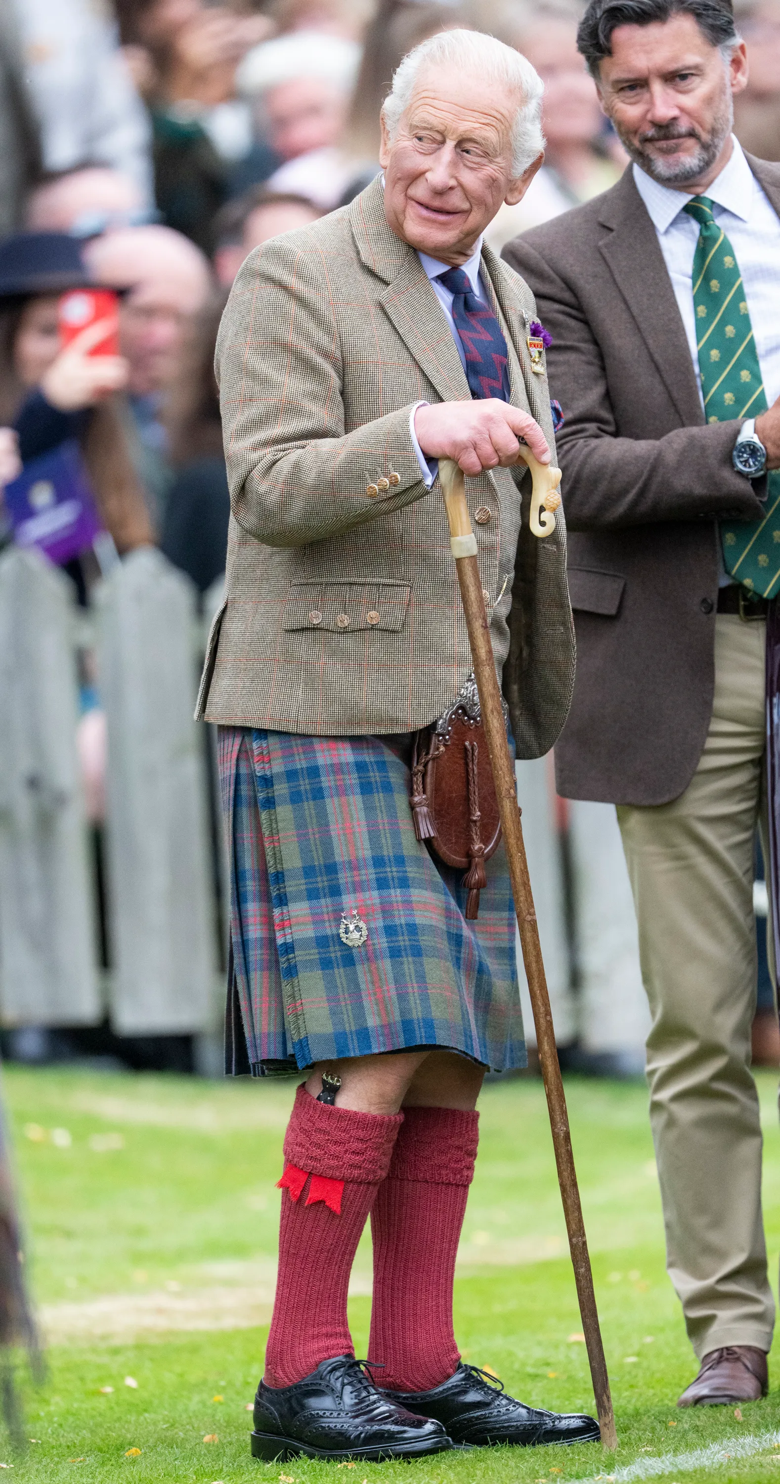 King Charles III wearing a kilt and holding a walking stick at The Braemar Gathering.