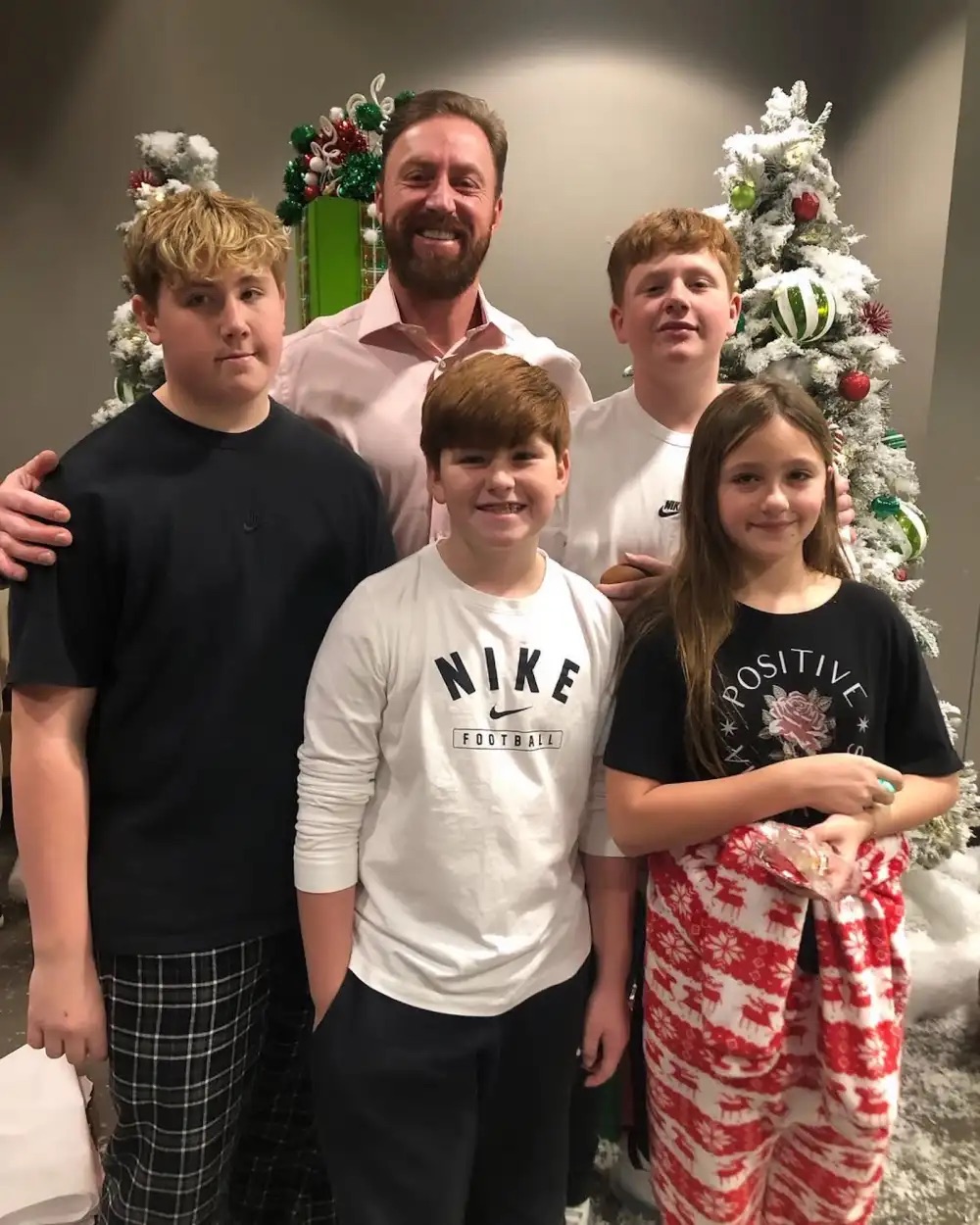 Kroy Biermann posing with his children Kroy Jr., Kash, Kaia, and Kane in front of a Christmas tree.