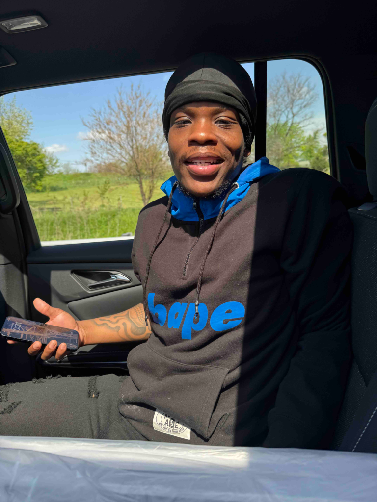 Kyle Bickham smiling in a vehicle, wearing a black beanie and a black hoodie with 