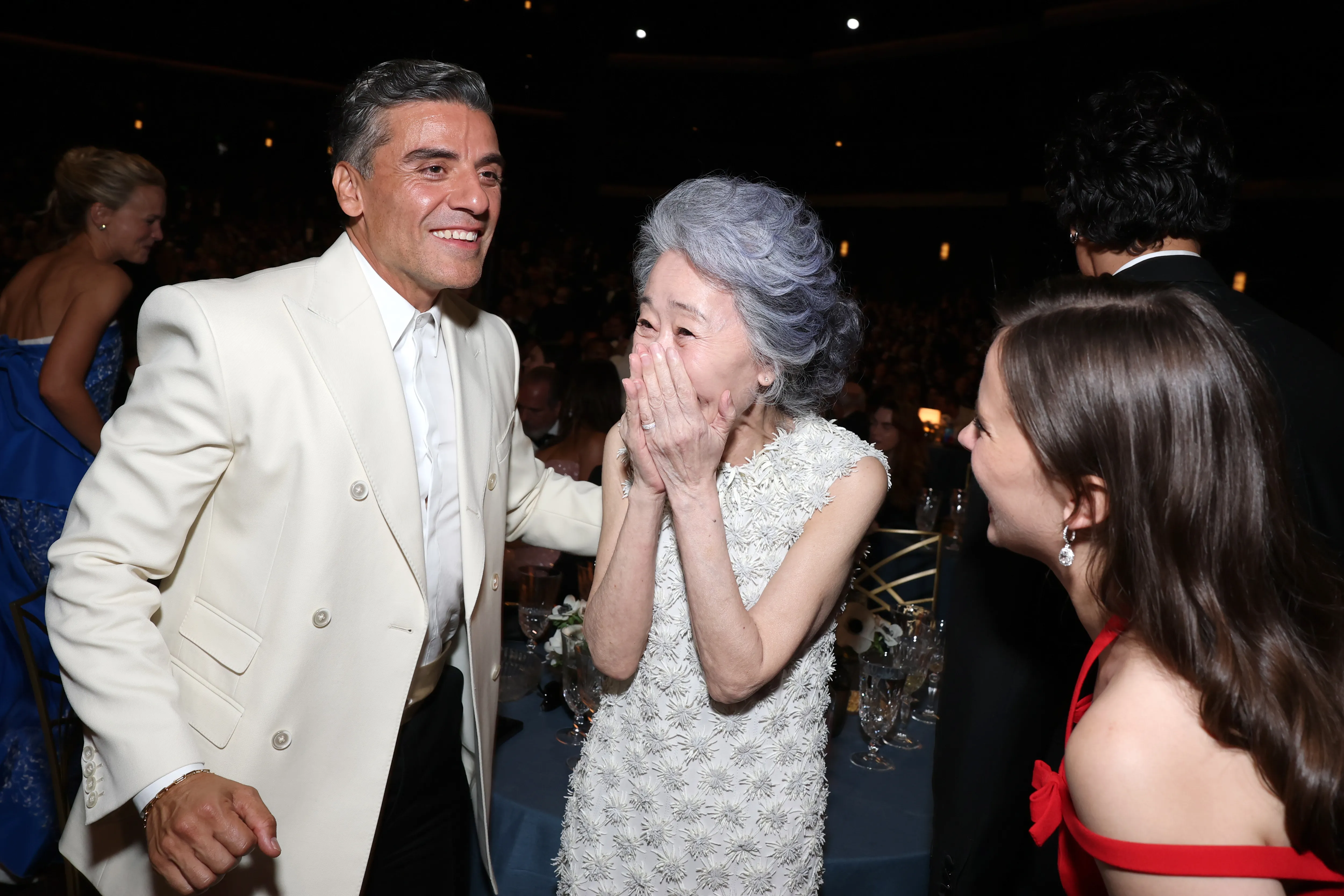 Oscar Isaac smiling at Youn Yuh-jung, who is covering her mouth with her hands in surprise at the 78th Primetime Emmy Awards.