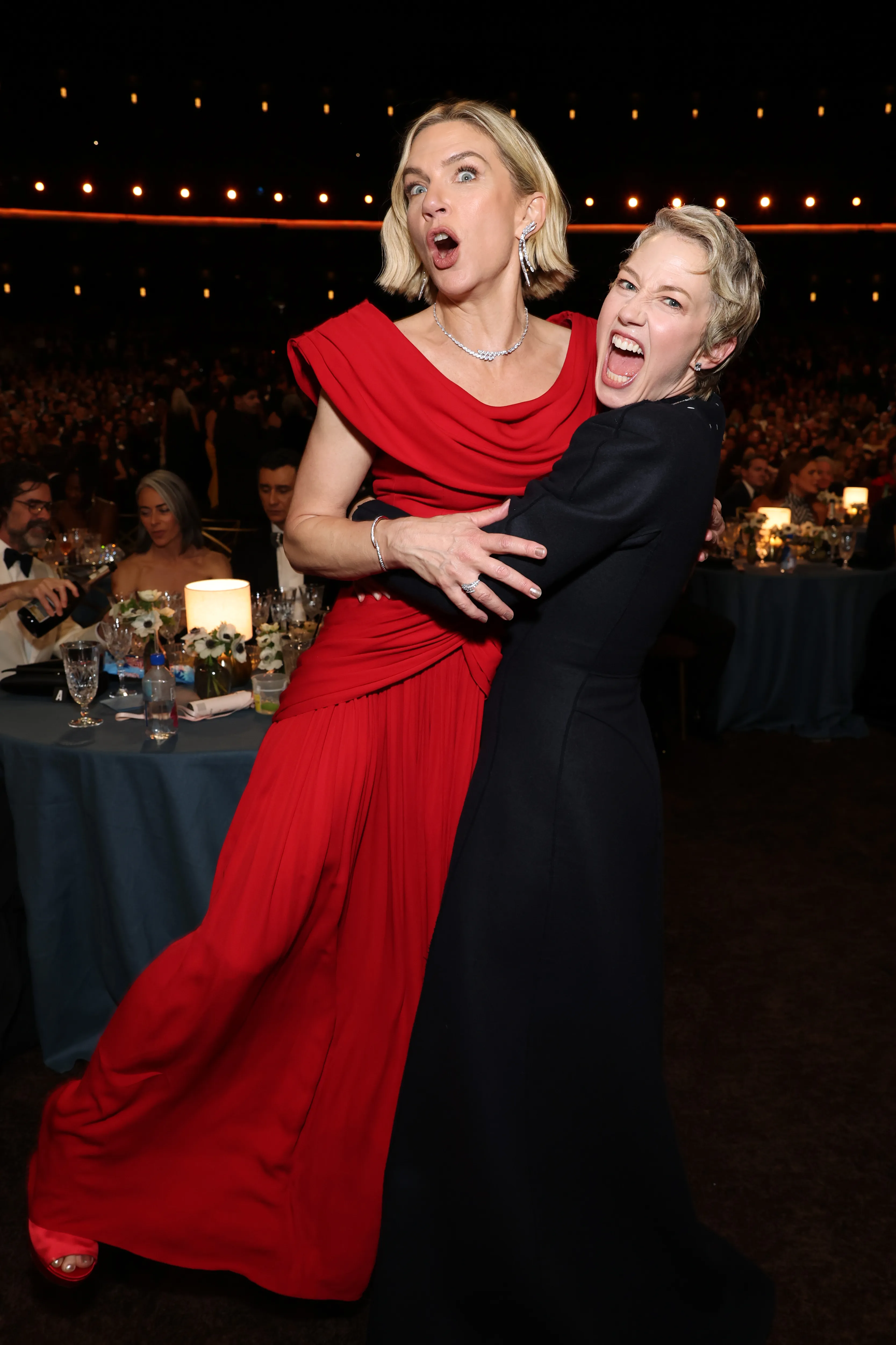 Rhea Seehorn in a red dress and Carrie Coon in a black dress embrace, making silly faces at an awards ceremony.