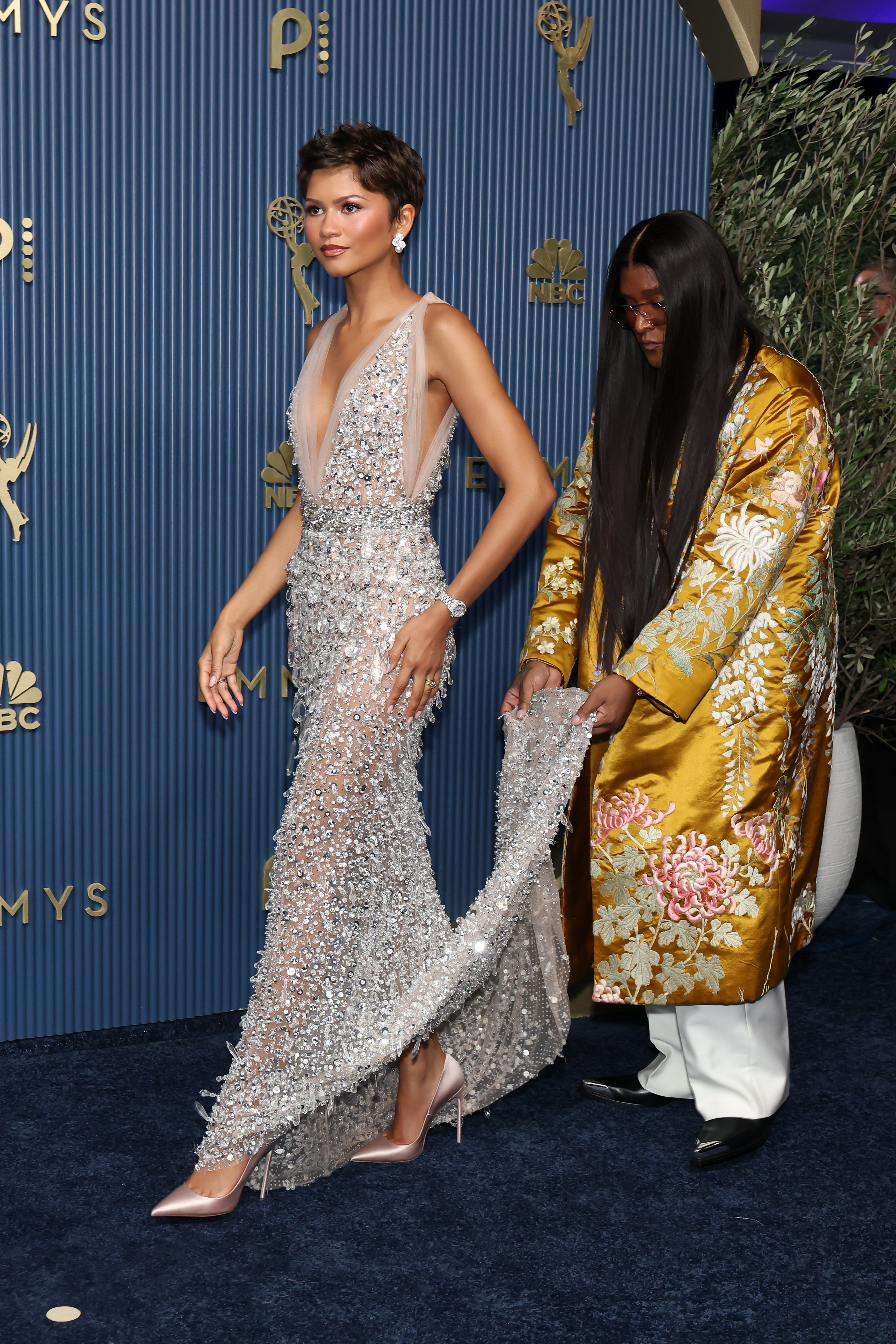 Zendaya in a sparkling, sleeveless gown, with Law Roach adjusting her train at the 78th Primetime Emmy Awards.