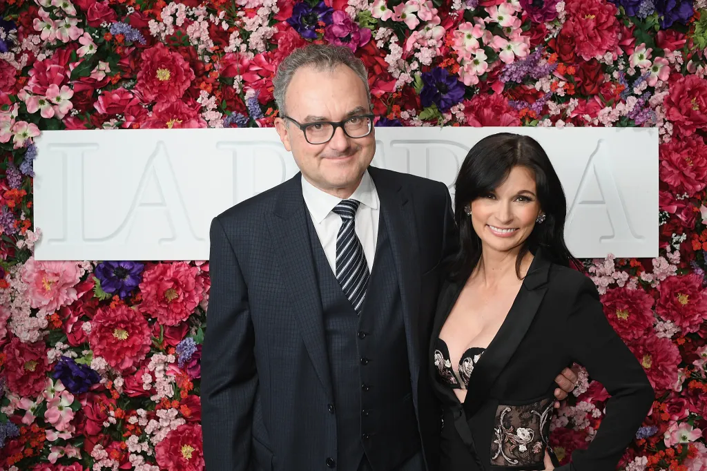 Silvio Scaglia and Julia Haart posing together against a flower wall.