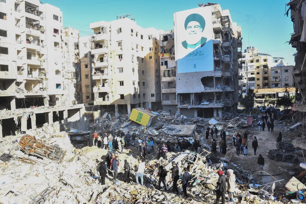 Lebanese people visiting Haret Hreik, an area of the Dahieh neighborhood that was damaged during an Israeli attack, with a large banner of Hezbollah leader Hassan Nasrallah on a damaged building.