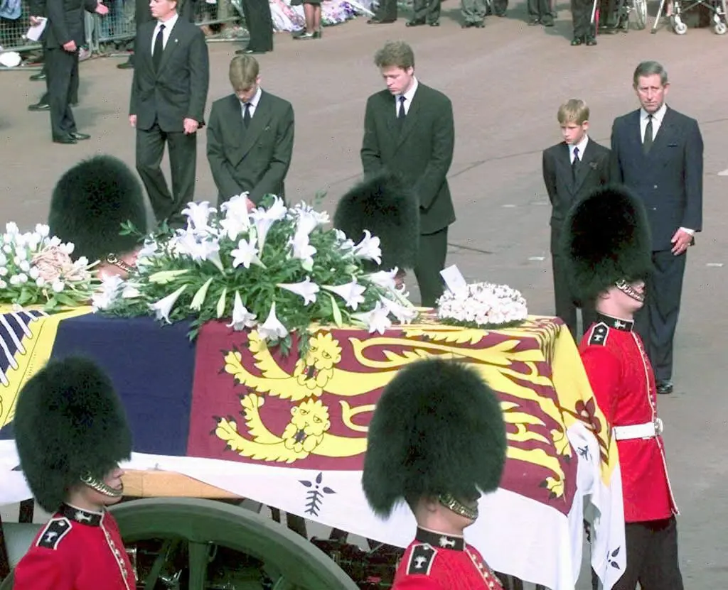 Prince William, Earl Spencer, Prince Harry, and Prince Charles follow Diana's coffin, all in black suits.