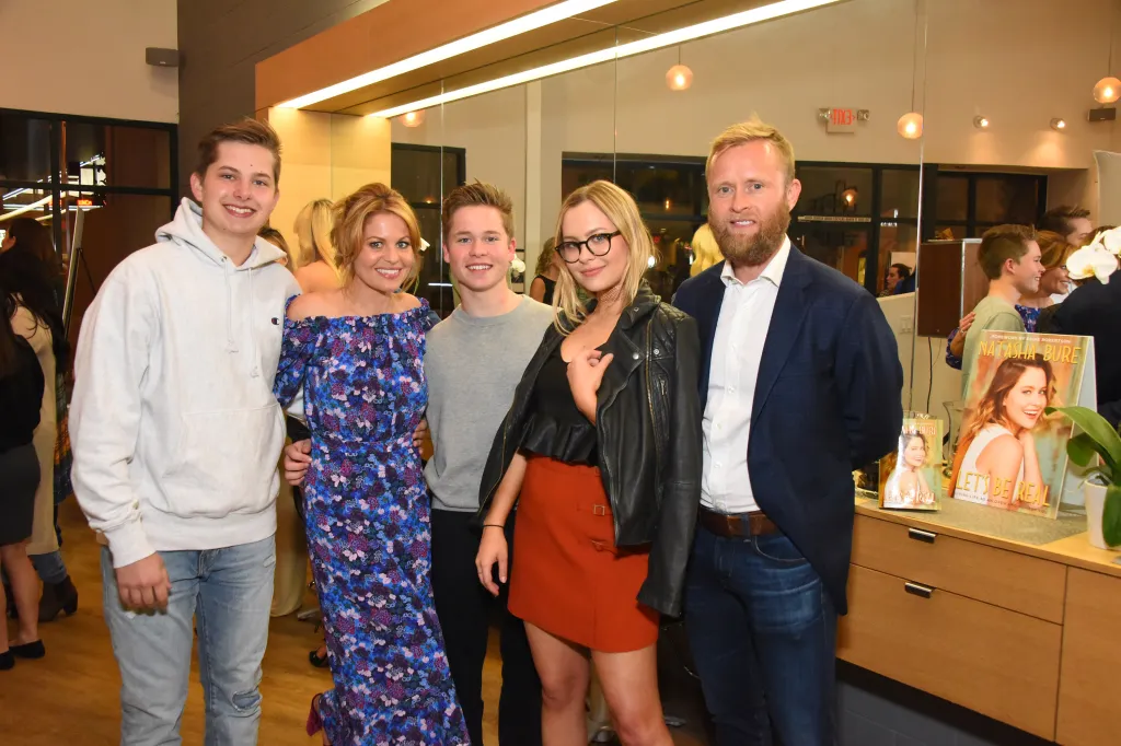 Candace Cameron Bure and her family posing with Natasha Bure's book