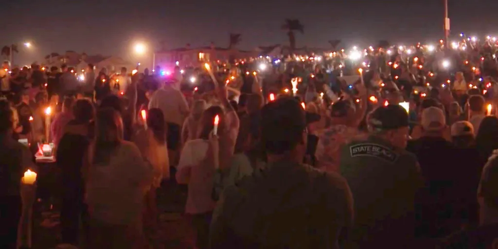 People gather at South Tamarack Jetty at night, holding candles in tribute to Vanessa Wheyland.