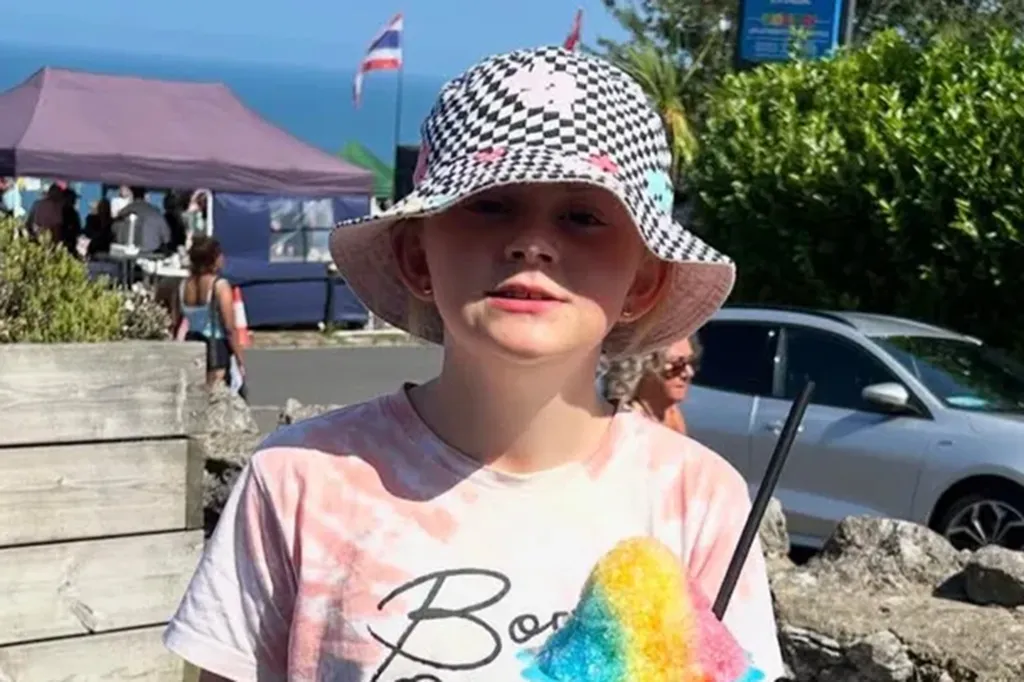 Lilly Angel Rodgers, 11, holding a rainbow shaved ice, wearing a black and white checkerboard bucket hat and tie-dye shirt.