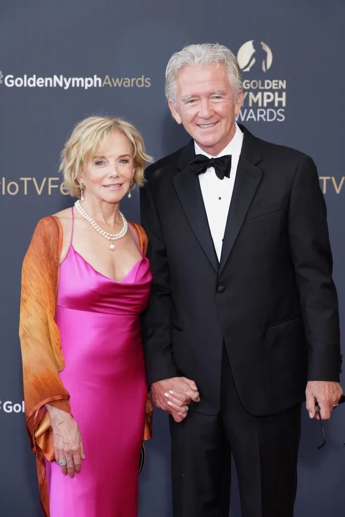 Linda Purl and Patrick Duffy holding hands on a red carpet.