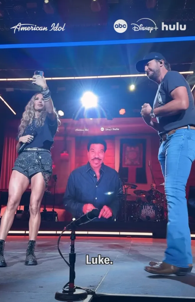 Two people on stage with an image of Lionel Richie between them, with 