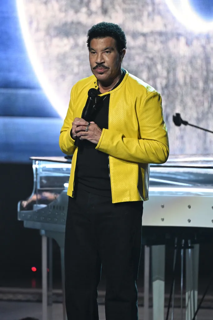 Lionel Richie performing at Hard Rock Live in a yellow jacket, holding a microphone.