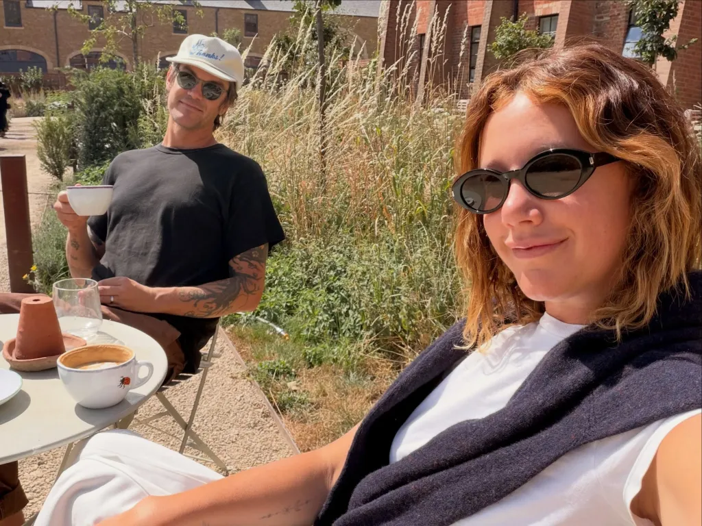 Ashley Tisdale and her husband having coffee outdoors on a sunny day.