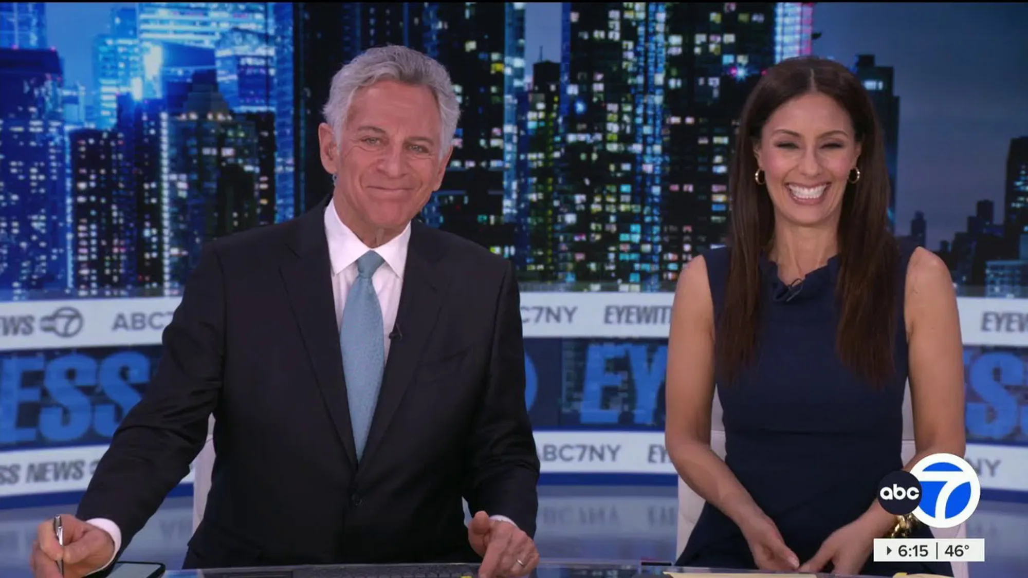 Liz Cho and a male co-anchor smiling at the news desk.