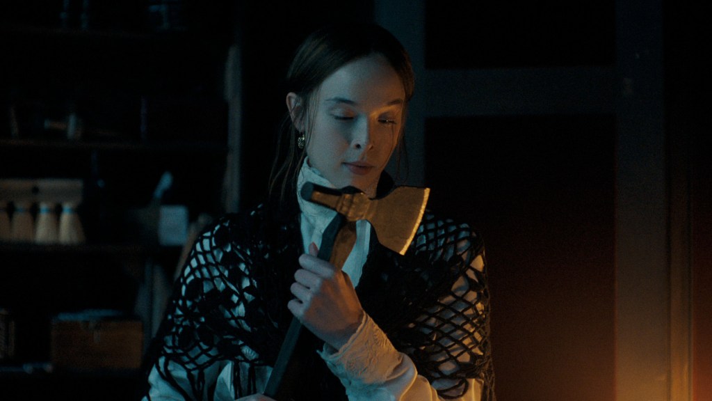 Ella Beatty as Lizzie Borden holding an axe.