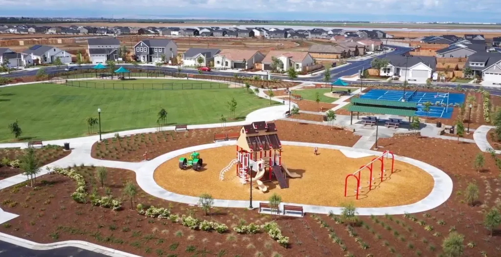 Aerial view of Gossamer Grove, a new masterplan community in Shafter, CA, showing new homes, a green park, playground, and sports court.