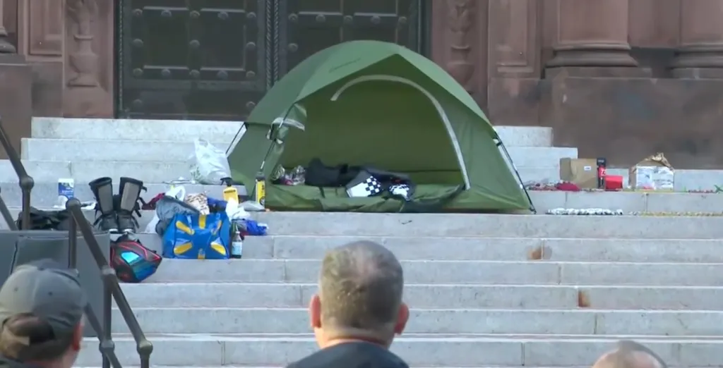 Green tent and items scattered on the steps of the Cathedral of St. Matthew the Apostle.