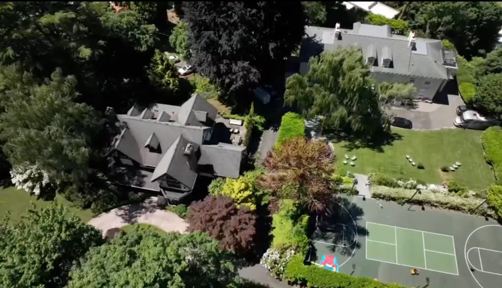 Aerial view of Macklemore's Seattle home, showing two large houses, a tennis/basketball court, and expansive green lawns and trees.