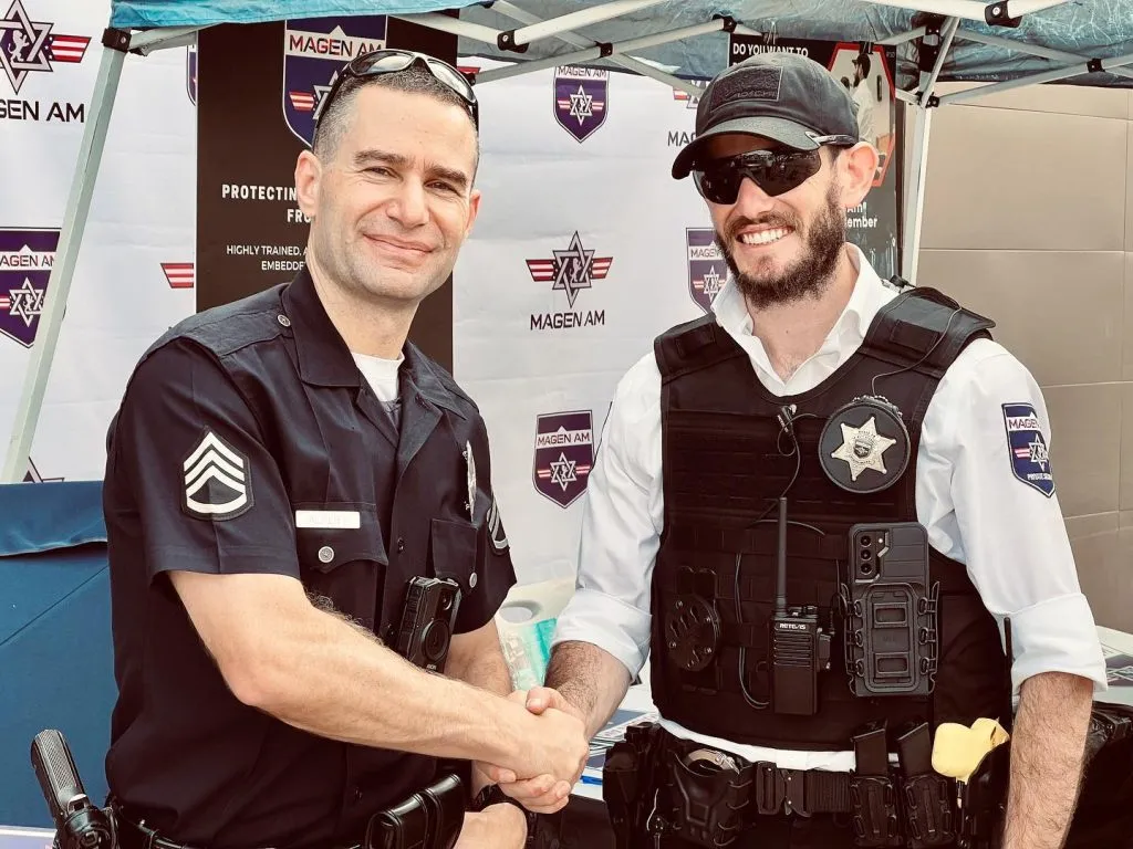 An LAPD officer and a Magen Am representative shaking hands.