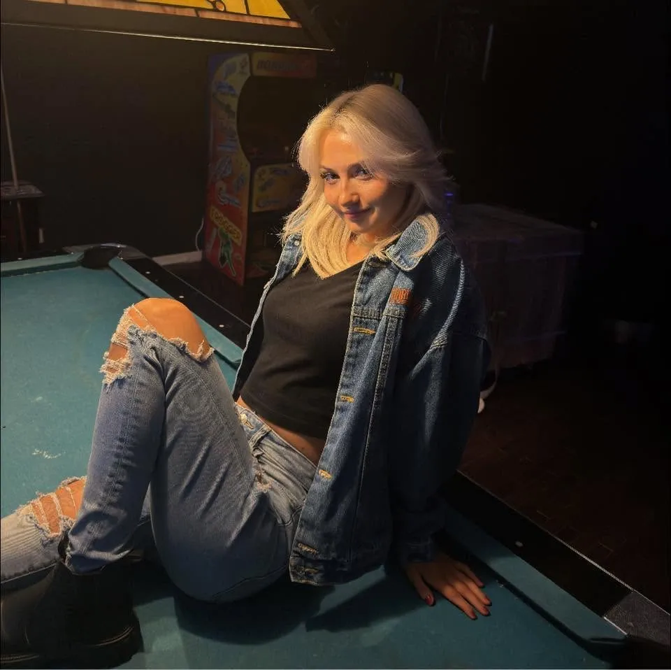 CloeRae McBrayer smiling and sitting on a pool table.