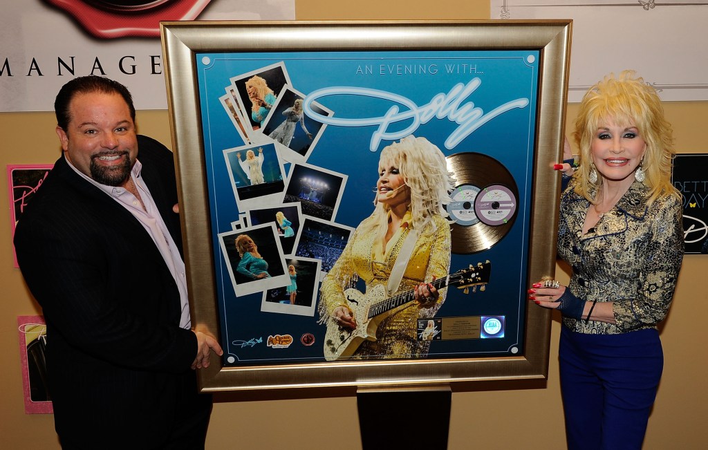 Manager Danny Nozell and Dolly Parton pose with a framed 
