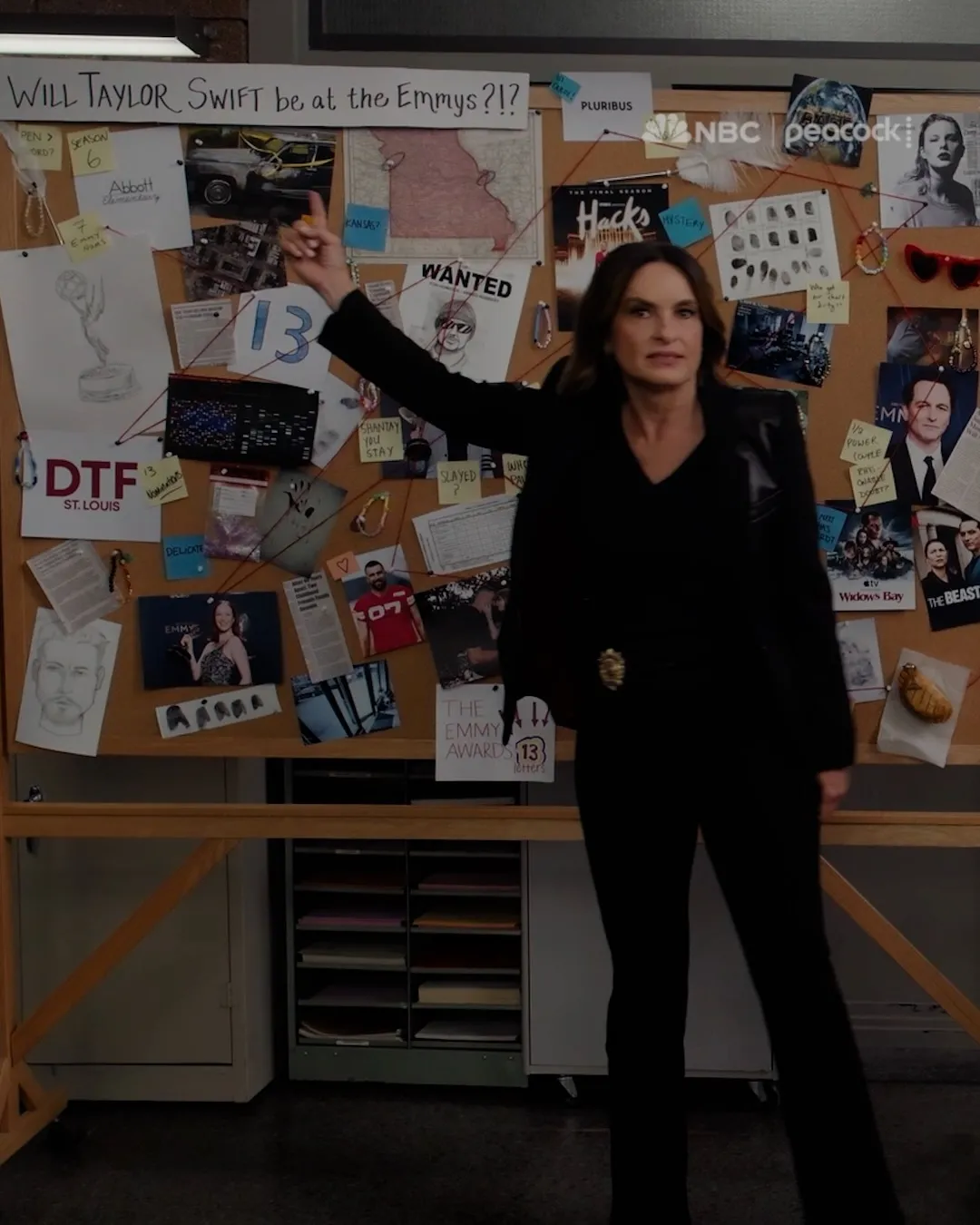 Mariska Hargitay points at a corkboard filled with images and notes about Taylor Swift and the Emmys.