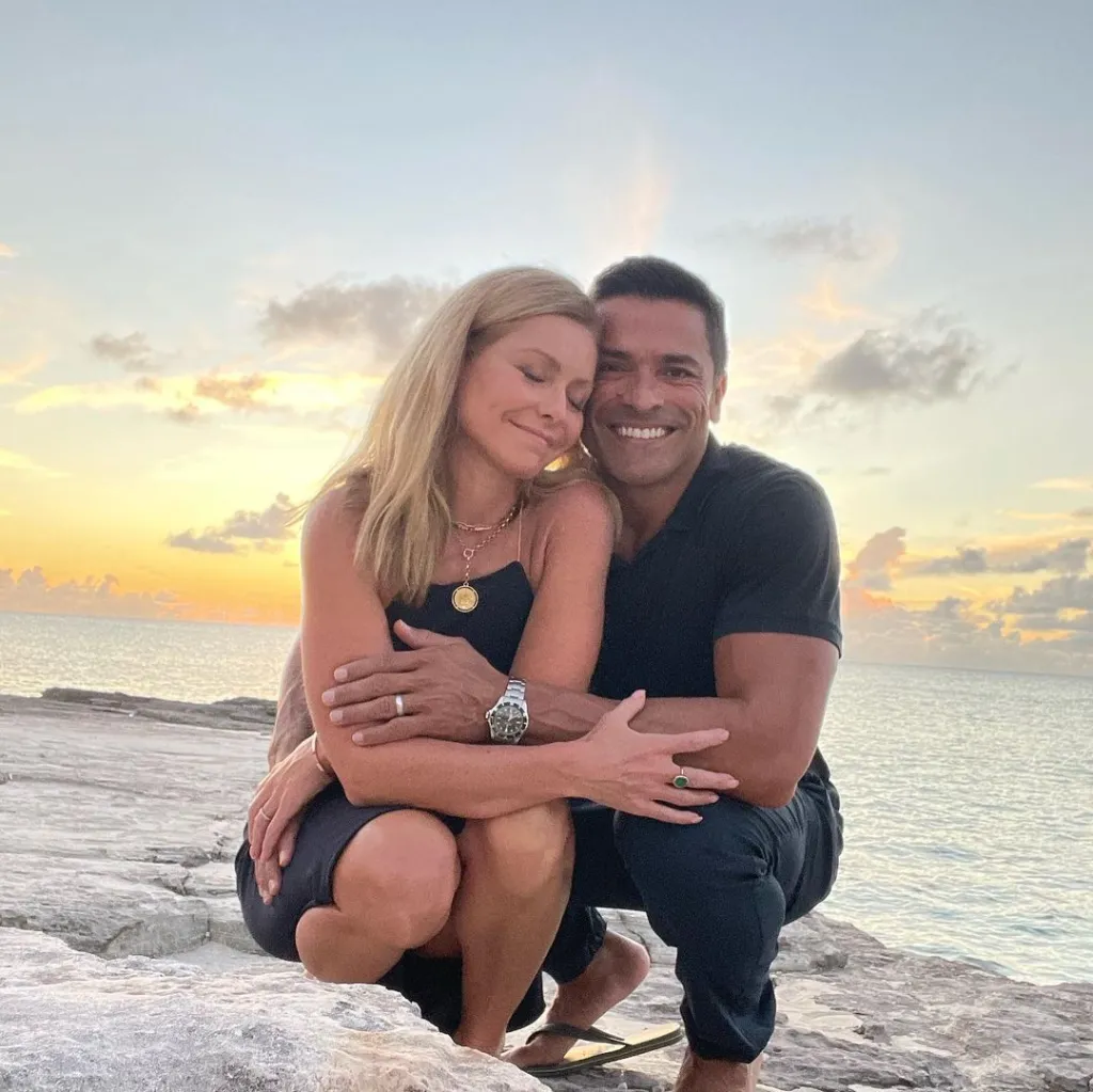 Mark Consuelos and Kelly Ripa embracing by the ocean at sunset.