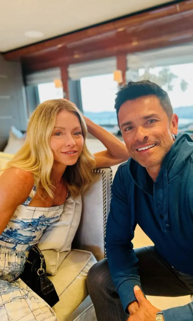 Mark Consuelos and Kelly Ripa pose for a selfie, with Kelly wearing a blue and white patterned top and Mark in a blue hoodie.