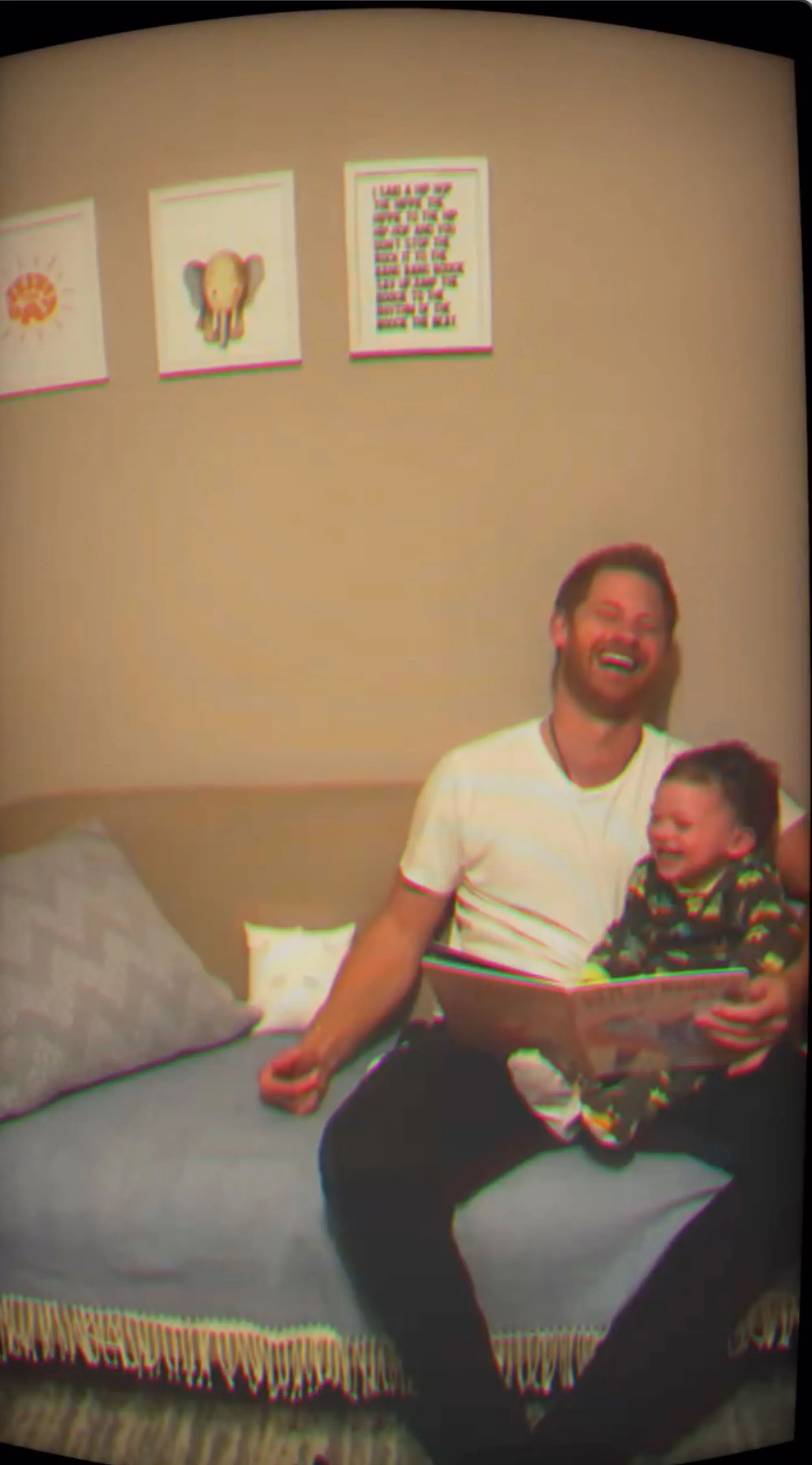 Prince Harry and Archie laughing while reading a book.