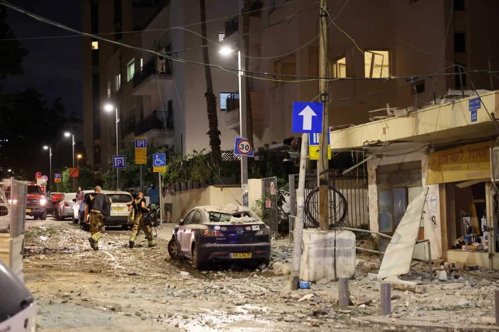 Members of Israeli security forces walk along a debris-strewn street in Tel Aviv after a rocket attack.