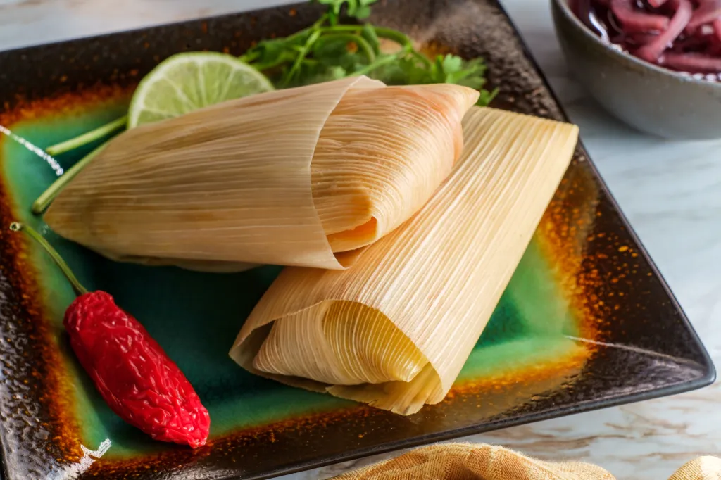 Mexican steamed chili and cheese masa tamales wrapped in corn husk.
