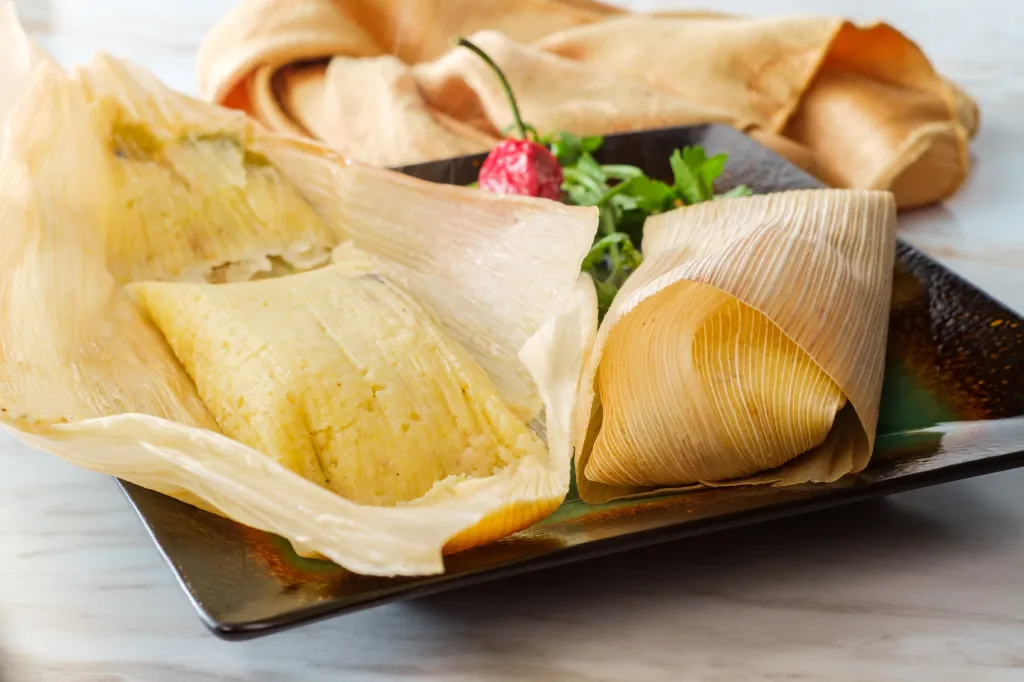 Mexican chili cheese corn tamales wrapped in corn husks.