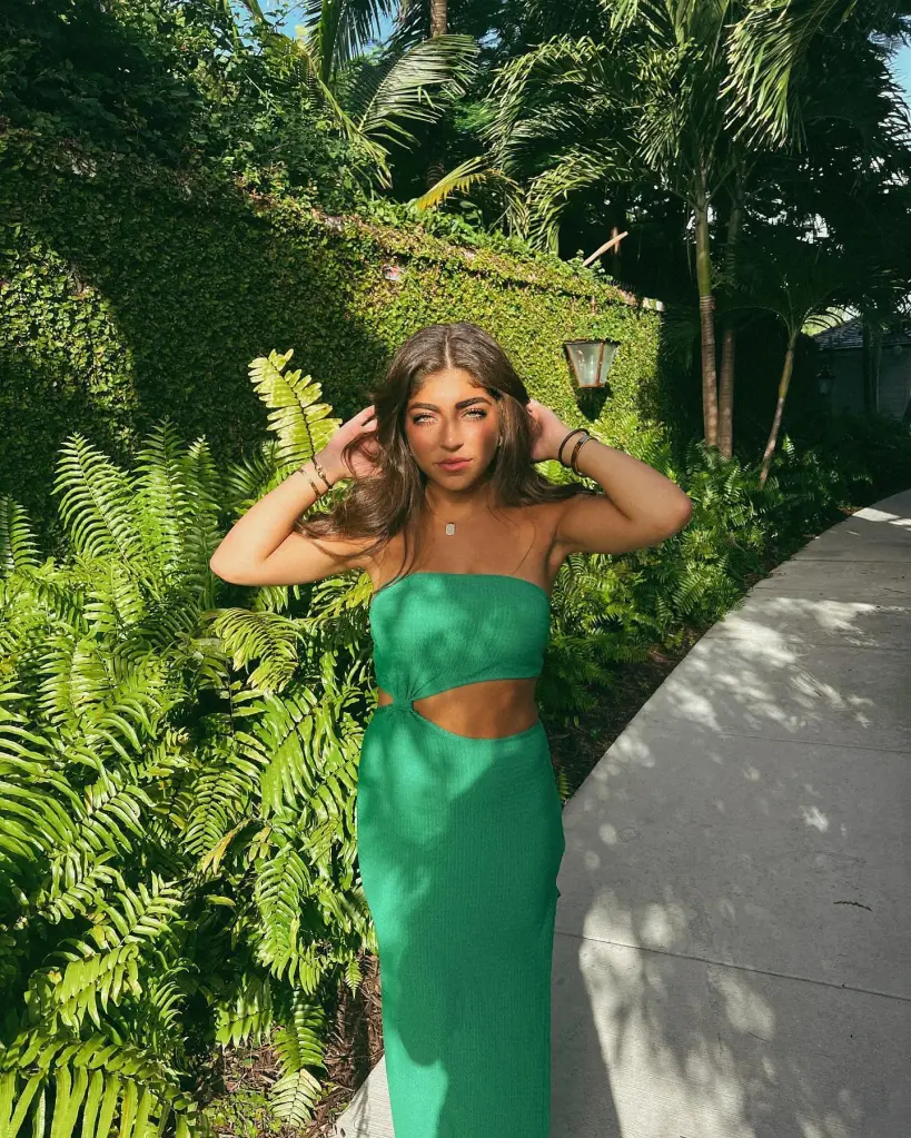 Milania Giudice posing in a green outfit with tropical plants in the background.