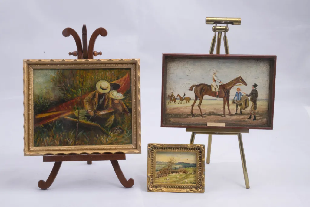 Miniature artworks of a person in a canoe, a horse with a rider, and a pastoral landscape.