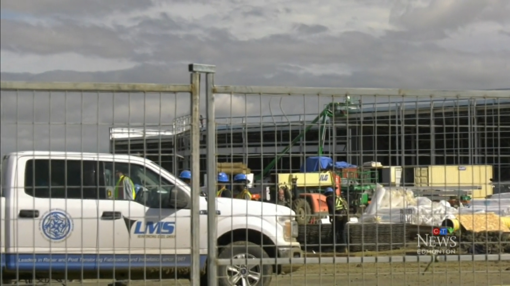 Construction of a new Costco location in Edmonton, with a white truck, metal fence, workers, and building materials.